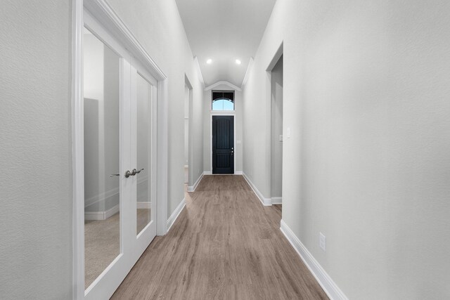 hallway with light hardwood / wood-style floors and vaulted ceiling