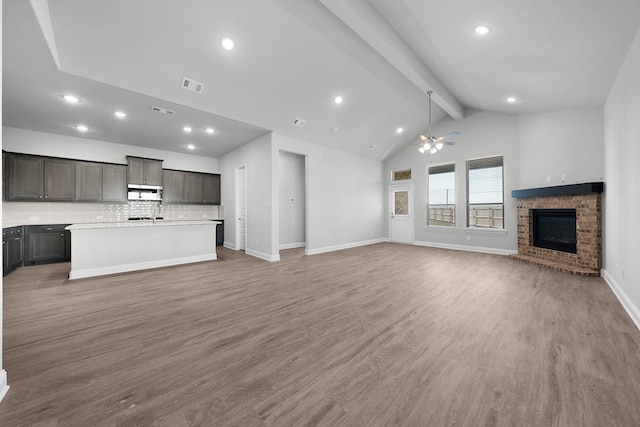 unfurnished living room featuring beam ceiling, ceiling fan, high vaulted ceiling, wood-type flooring, and a fireplace