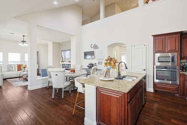 dining room with ceiling fan, dark hardwood / wood-style flooring, sink, and high vaulted ceiling