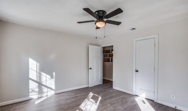 unfurnished bedroom with dark hardwood / wood-style flooring, a closet, and ceiling fan