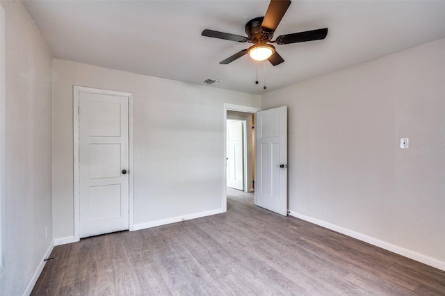 spare room with visible vents, baseboards, and wood finished floors