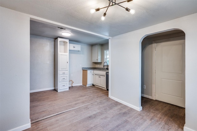 interior space featuring light hardwood / wood-style flooring, white cabinets, and a textured ceiling