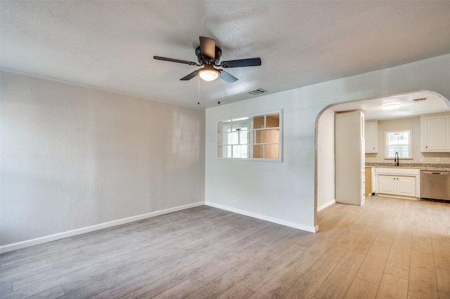 spare room featuring a textured ceiling, ceiling fan, sink, and light hardwood / wood-style flooring