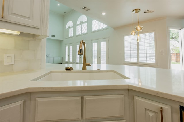 kitchen with hanging light fixtures, sink, white cabinets, and a healthy amount of sunlight