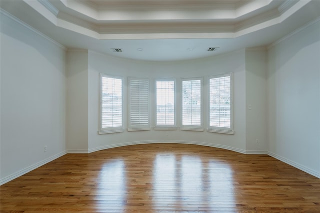 unfurnished room featuring a raised ceiling, crown molding, and hardwood / wood-style floors