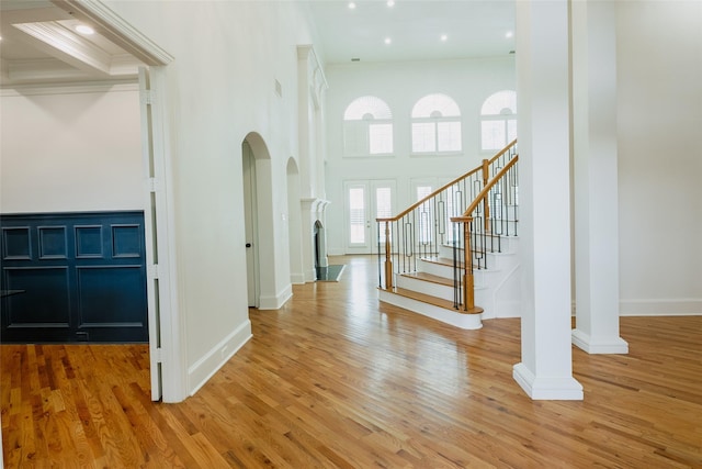 entrance foyer with hardwood / wood-style floors, beam ceiling, and a towering ceiling