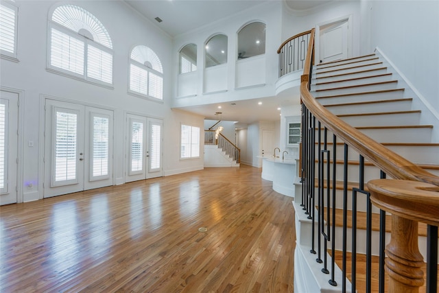 unfurnished living room featuring a towering ceiling and light wood-type flooring