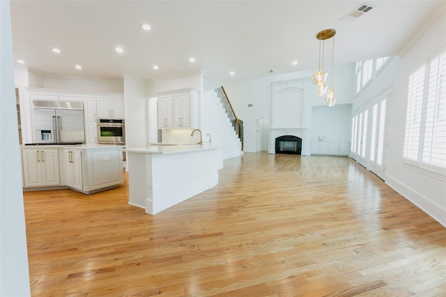 kitchen with pendant lighting, built in fridge, plenty of natural light, and light hardwood / wood-style floors