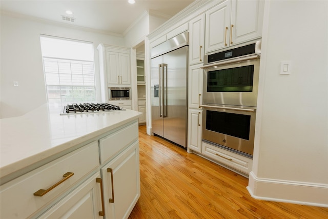 kitchen with built in appliances, light hardwood / wood-style floors, white cabinetry, and crown molding