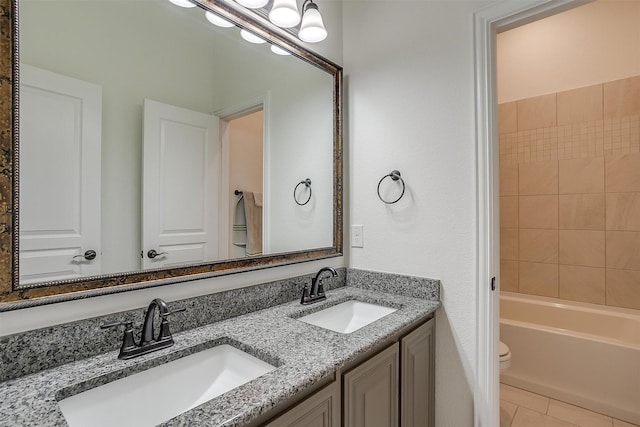 full bathroom with tile patterned floors, vanity, tiled shower / bath combo, and toilet