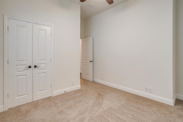 unfurnished bedroom with light carpet, a closet, and ceiling fan