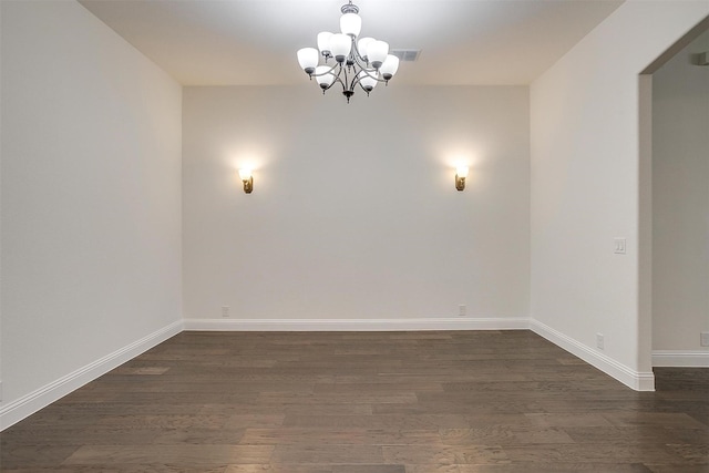 unfurnished room with a chandelier and dark wood-type flooring