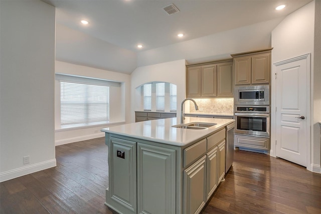 kitchen with sink, vaulted ceiling, decorative backsplash, an island with sink, and appliances with stainless steel finishes