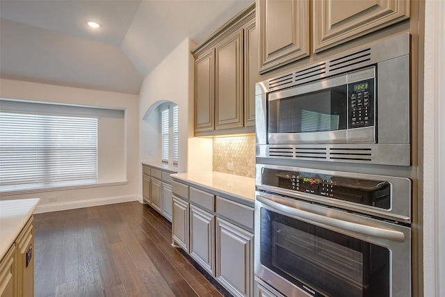 kitchen featuring dark hardwood / wood-style flooring, lofted ceiling, backsplash, and appliances with stainless steel finishes