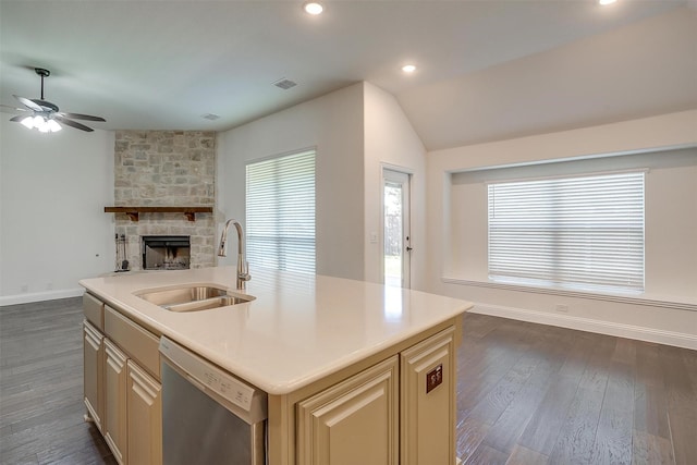 kitchen featuring dishwasher, sink, a stone fireplace, dark hardwood / wood-style floors, and a center island with sink