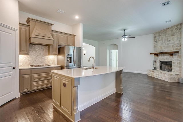 kitchen featuring sink, an island with sink, a fireplace, appliances with stainless steel finishes, and custom exhaust hood