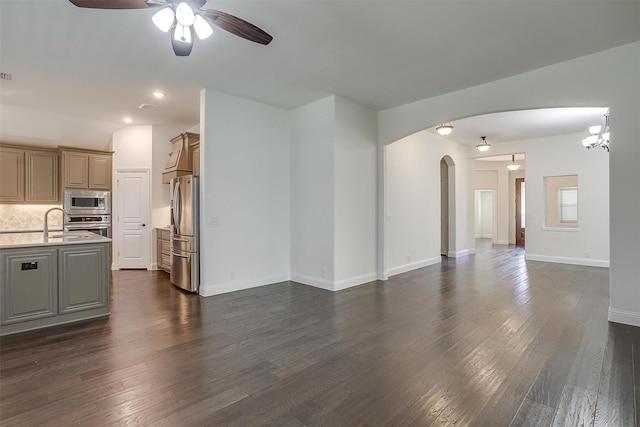 unfurnished living room featuring ceiling fan with notable chandelier, dark hardwood / wood-style floors, and sink