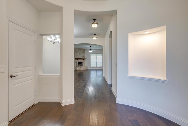 corridor with dark hardwood / wood-style floors and an inviting chandelier