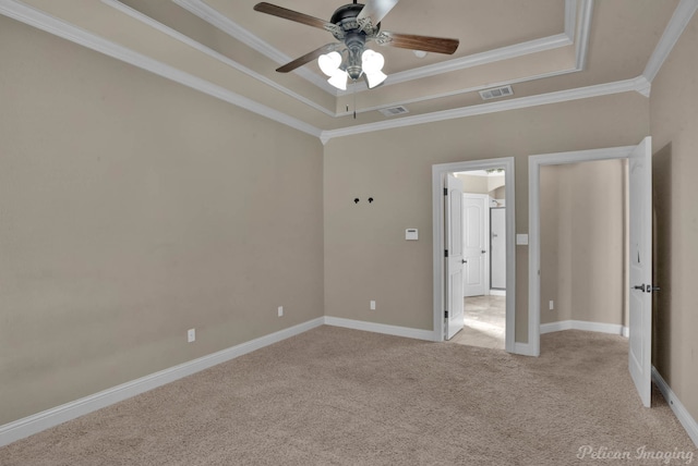 unfurnished bedroom with ceiling fan, light colored carpet, ornamental molding, and a tray ceiling