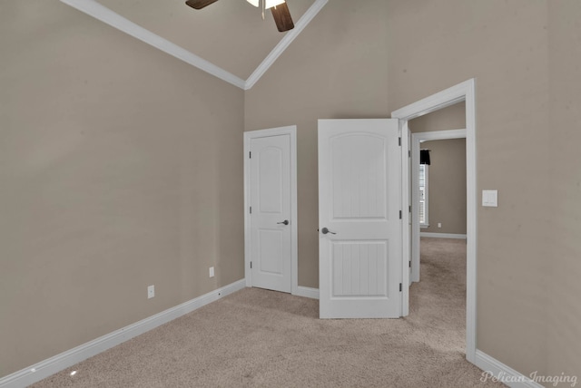 unfurnished bedroom featuring light colored carpet, high vaulted ceiling, and ceiling fan