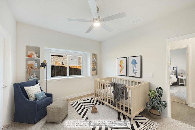 carpeted bedroom featuring ceiling fan and a crib