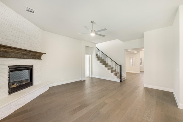 unfurnished living room with a stone fireplace, ceiling fan, and wood-type flooring