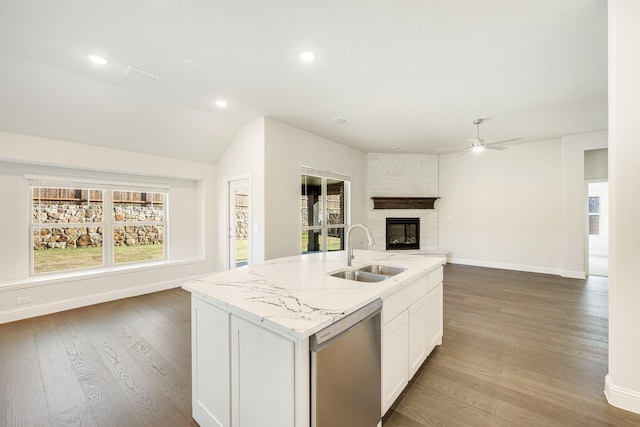 kitchen featuring dishwasher, sink, light stone countertops, an island with sink, and white cabinetry