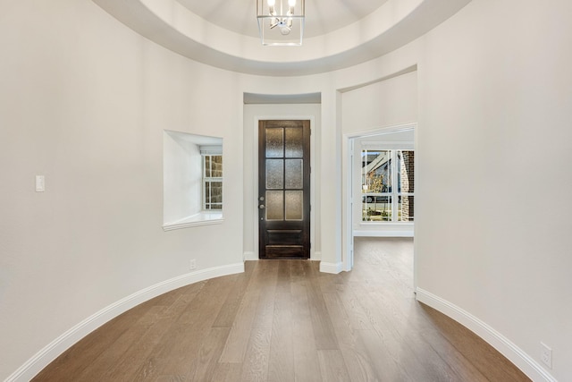 entryway with a chandelier, wood-type flooring, and a raised ceiling