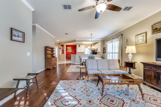 living room featuring ceiling fan with notable chandelier, dark hardwood / wood-style floors, and ornamental molding