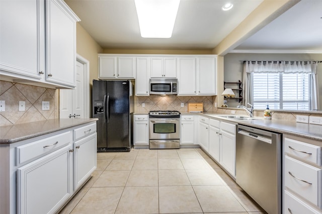 kitchen featuring decorative backsplash, stainless steel appliances, white cabinetry, and sink