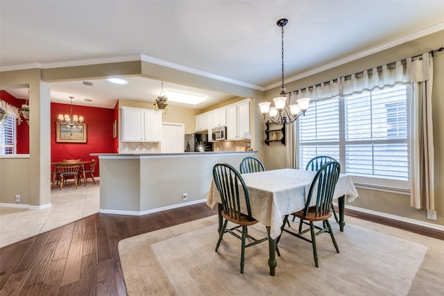 dining area with crown molding, light hardwood / wood-style floors, and a notable chandelier