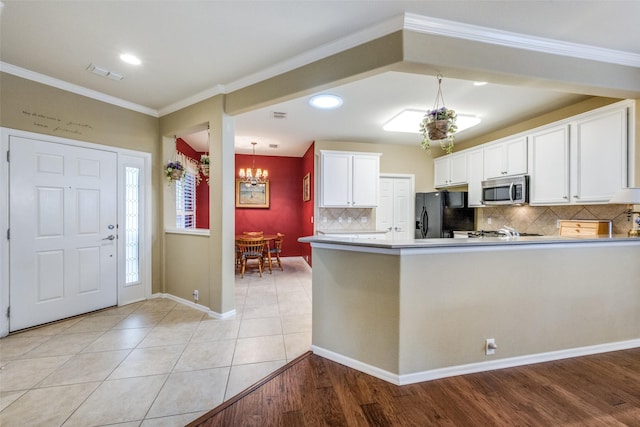 kitchen featuring white cabinets, light hardwood / wood-style floors, black fridge with ice dispenser, and a chandelier