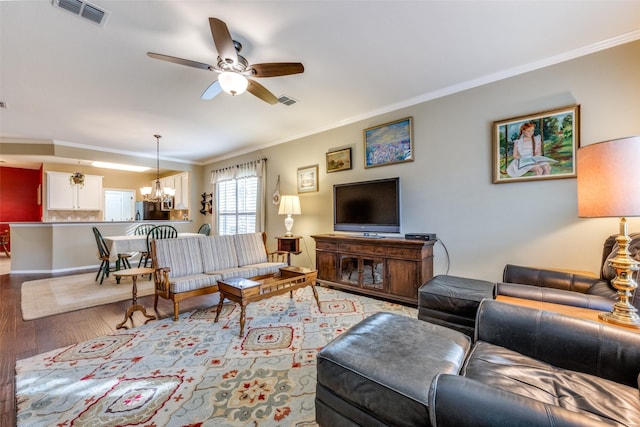 living room with crown molding, ceiling fan with notable chandelier, and light wood-type flooring