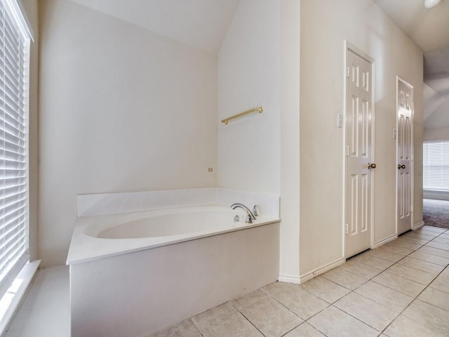 bathroom featuring a tub to relax in, tile patterned floors, and vaulted ceiling