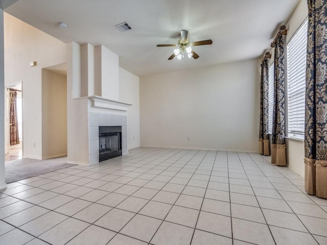 unfurnished living room with light tile patterned floors, a tile fireplace, and ceiling fan