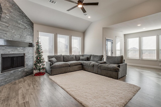 living room featuring vaulted ceiling, ceiling fan, a fireplace, and light hardwood / wood-style flooring