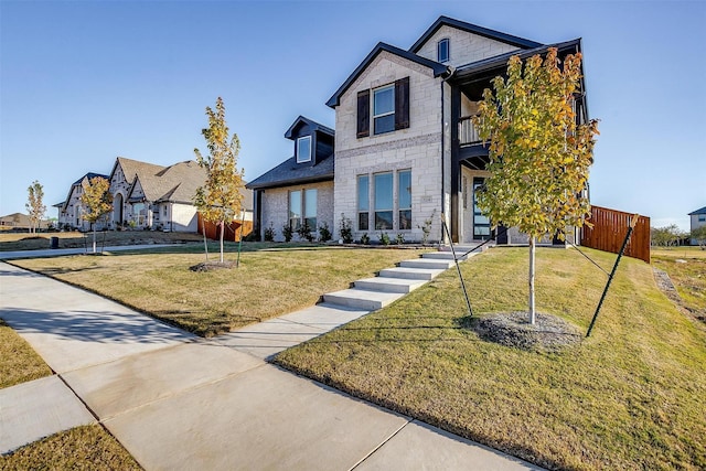 view of front of home with a balcony and a front lawn