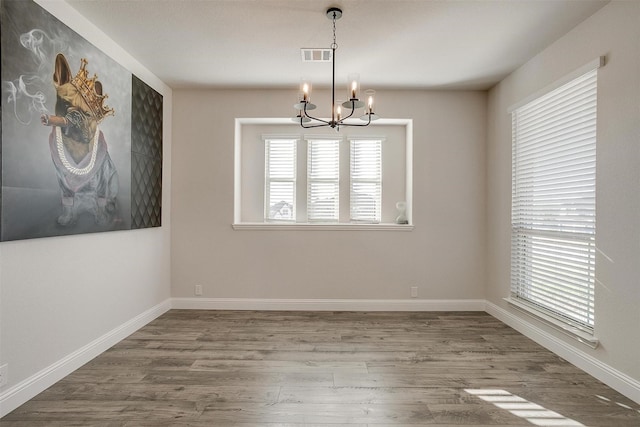 spare room with a chandelier and hardwood / wood-style flooring