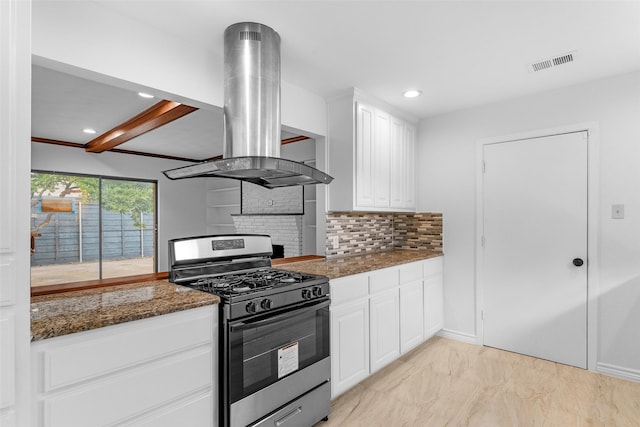 kitchen featuring island exhaust hood, white cabinetry, stainless steel range with gas cooktop, and dark stone countertops