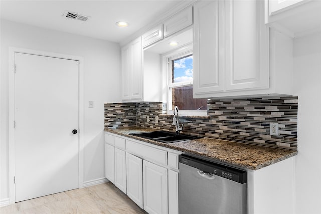 kitchen with tasteful backsplash, stainless steel dishwasher, dark stone counters, sink, and white cabinetry