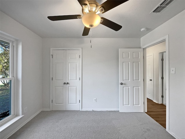 unfurnished bedroom with dark colored carpet, ceiling fan, and a closet