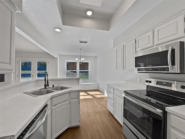 kitchen featuring dark hardwood / wood-style flooring, stainless steel appliances, sink, decorative light fixtures, and white cabinets