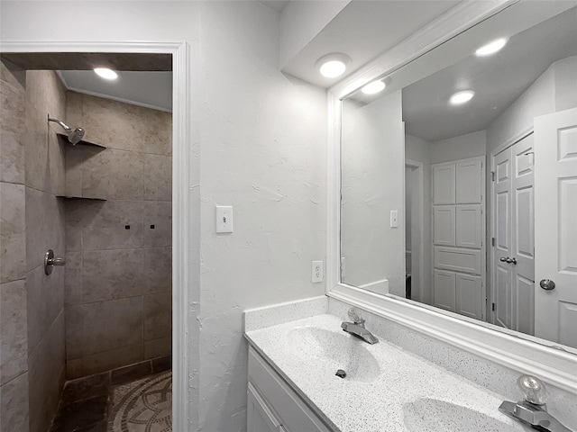 bathroom with a tile shower and vanity