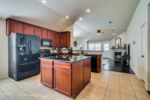 kitchen with kitchen peninsula, vaulted ceiling, sink, black appliances, and a center island