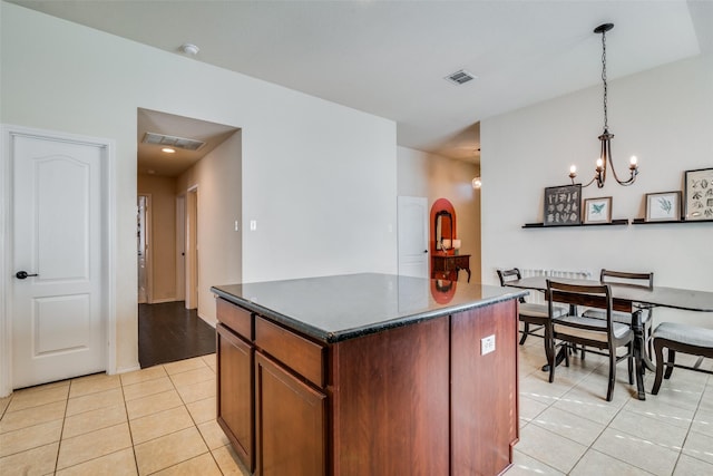 kitchen featuring pendant lighting, a center island, light tile patterned flooring, and a chandelier