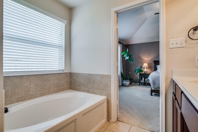 bathroom featuring vanity, tile patterned floors, a bathtub, and lofted ceiling