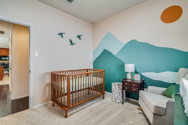 bedroom with a nursery area and wood-type flooring