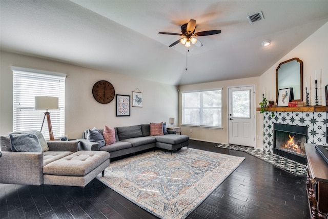 living room with a tile fireplace, ceiling fan, vaulted ceiling, and hardwood / wood-style flooring