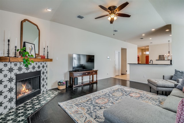 living room with a fireplace, ceiling fan with notable chandelier, and hardwood / wood-style flooring