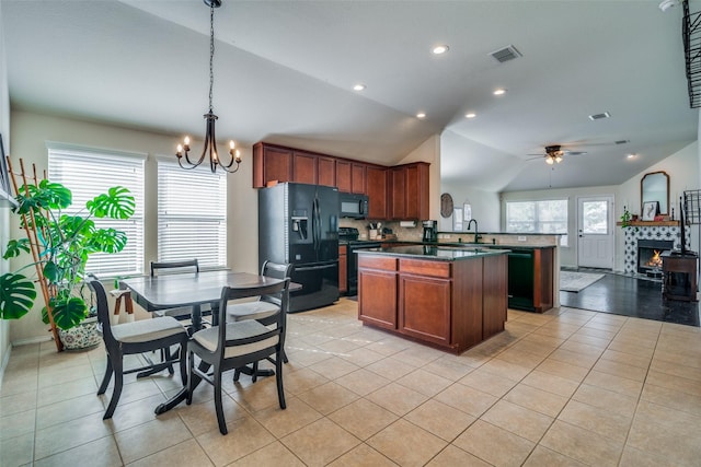 kitchen featuring lofted ceiling, black appliances, ceiling fan with notable chandelier, decorative light fixtures, and a tiled fireplace